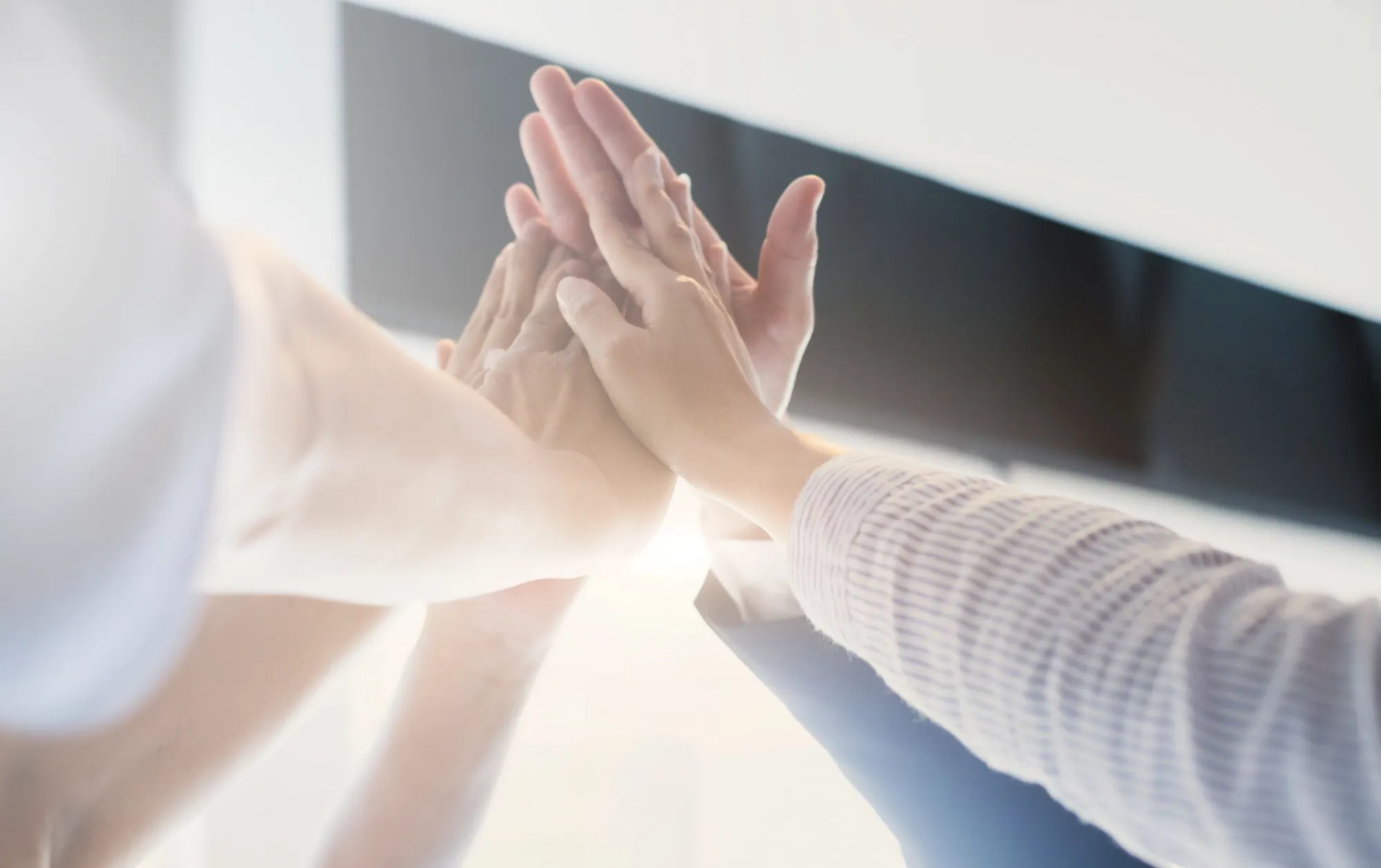 5 hands touching together in a 'high-five'.